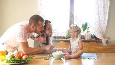 一个年轻的家庭花时间在厨房里，爸爸在他女儿的鼻子上放面粉。 幸福家庭概念